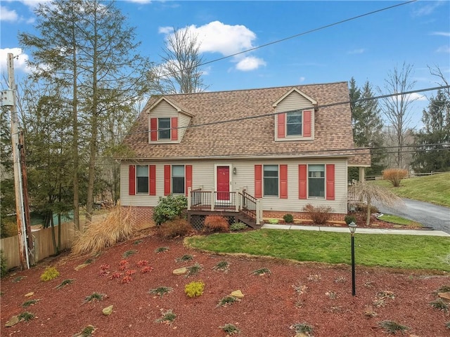 dutch colonial with a shingled roof, fence, and a front lawn