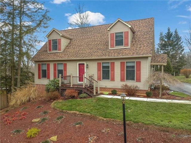 new england style home with a shingled roof and a front yard