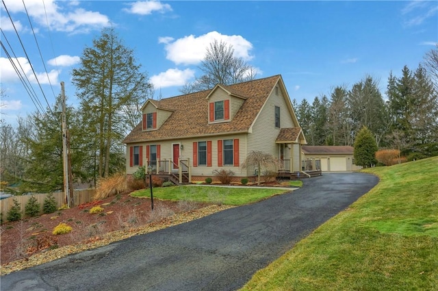 cape cod house featuring a detached garage, roof with shingles, an outbuilding, fence, and a front yard