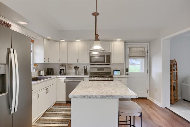 kitchen with stainless steel appliances, light countertops, light wood-style floors, white cabinetry, and a sink