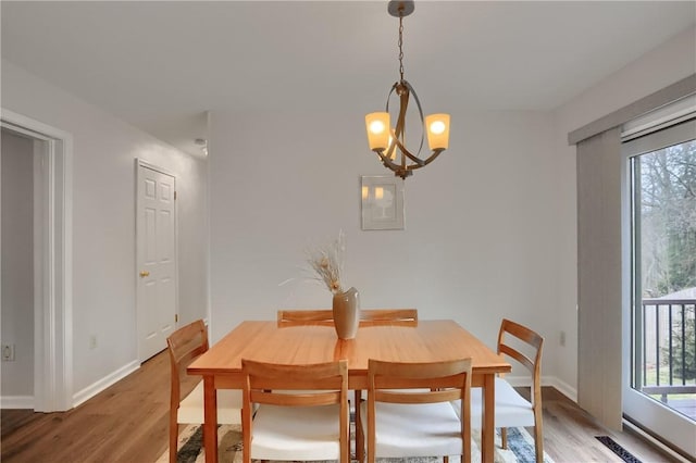 dining area featuring a healthy amount of sunlight, light wood-style flooring, baseboards, and an inviting chandelier