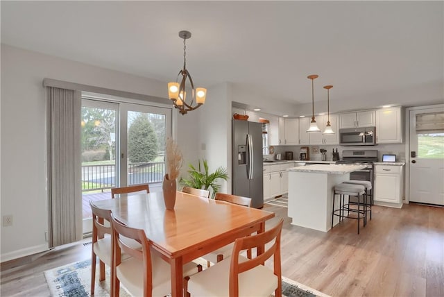 dining room with a notable chandelier, light wood-style flooring, baseboards, and a wealth of natural light