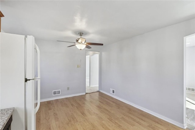 spare room with light wood-style floors, visible vents, ceiling fan, and baseboards