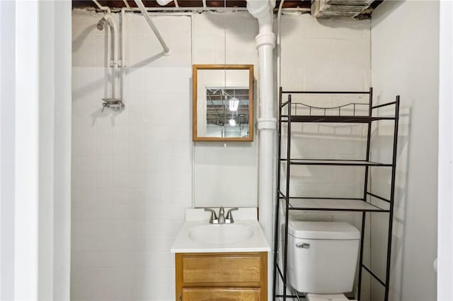 bathroom with toilet, a tile shower, and vanity