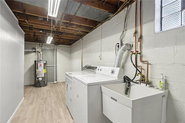 laundry area with light wood finished floors, water heater, a sink, washer and dryer, and laundry area