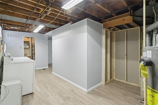 unfinished basement featuring baseboards, visible vents, wood finished floors, independent washer and dryer, and water heater