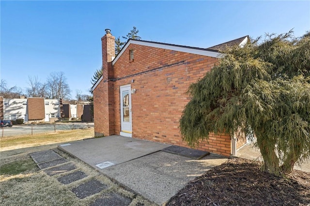 view of home's exterior featuring a chimney and brick siding