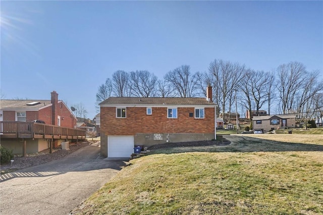 rear view of house with brick siding, a yard, a garage, a residential view, and driveway