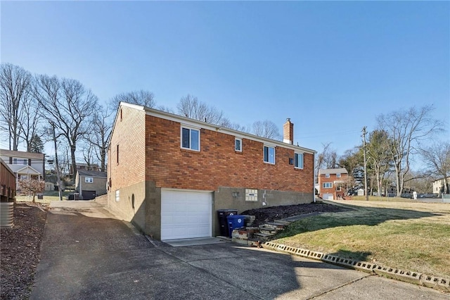 back of property with aphalt driveway, a garage, brick siding, a yard, and a chimney