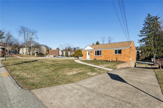 view of front of home featuring brick siding, a chimney, and a front yard