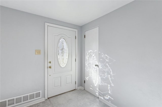 foyer featuring visible vents, light carpet, and baseboards