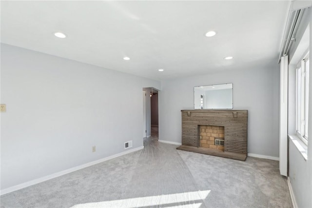 unfurnished living room with baseboards, visible vents, a fireplace with raised hearth, carpet floors, and recessed lighting