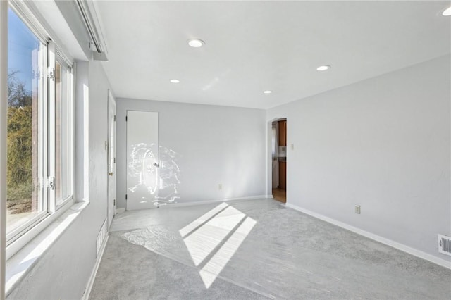 spare room featuring baseboards, arched walkways, and recessed lighting