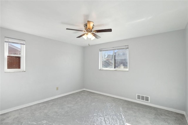 unfurnished room featuring a ceiling fan, visible vents, and baseboards