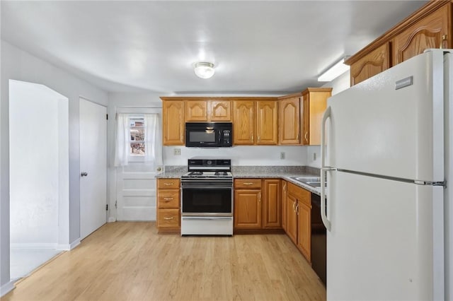 kitchen with brown cabinets, a sink, light wood-style flooring, and black appliances