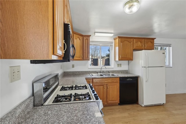 kitchen with light wood-type flooring, black appliances, brown cabinetry, and a sink