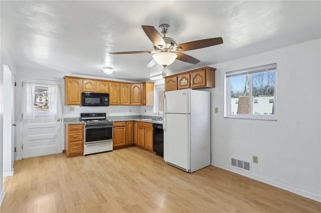 kitchen featuring visible vents, light countertops, light wood-type flooring, brown cabinets, and black appliances