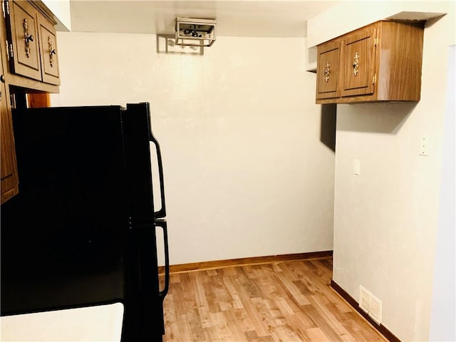 kitchen featuring visible vents, baseboards, freestanding refrigerator, brown cabinets, and light wood finished floors