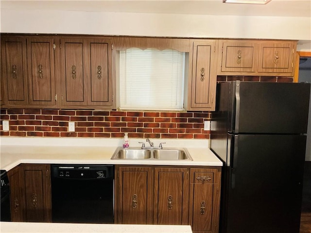 kitchen with black appliances, backsplash, a sink, and light countertops