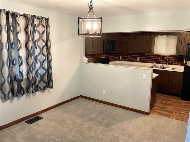 kitchen with visible vents, light countertops, backsplash, a sink, and black appliances