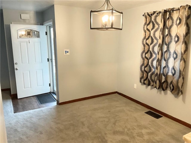 entryway featuring a notable chandelier, carpet flooring, visible vents, and baseboards