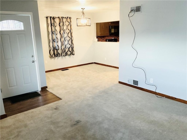 entryway with carpet floors, baseboards, and visible vents