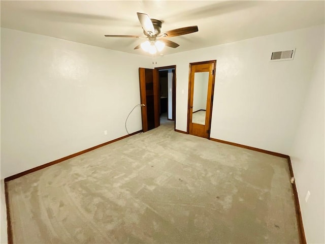 empty room featuring light carpet, baseboards, visible vents, and a ceiling fan