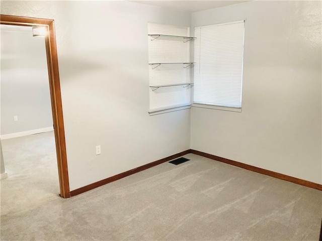 empty room featuring carpet, visible vents, and baseboards