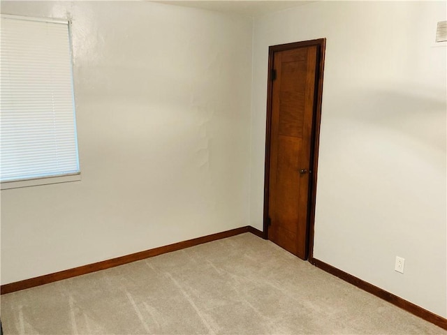 empty room with light colored carpet, visible vents, and baseboards