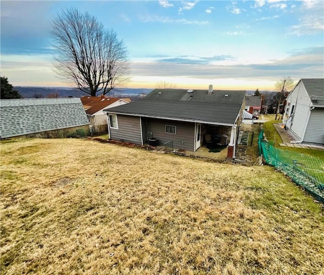 back of property featuring a yard and fence