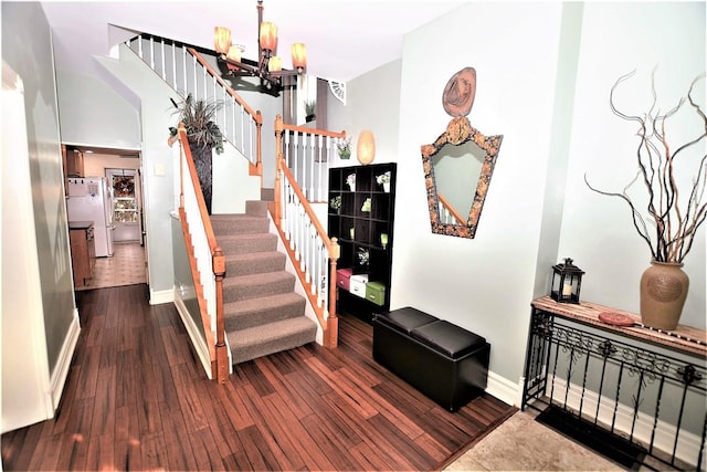 stairs with a chandelier, baseboards, and wood finished floors