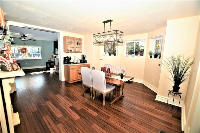 dining space featuring dark wood-type flooring, baseboards, and ceiling fan with notable chandelier
