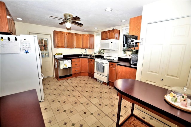 kitchen with recessed lighting, white appliances, brown cabinets, light floors, and dark countertops