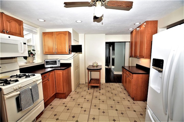 kitchen featuring white appliances, a toaster, dark countertops, brown cabinets, and light floors