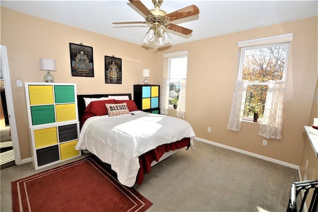 carpeted bedroom with ceiling fan, multiple windows, and baseboards