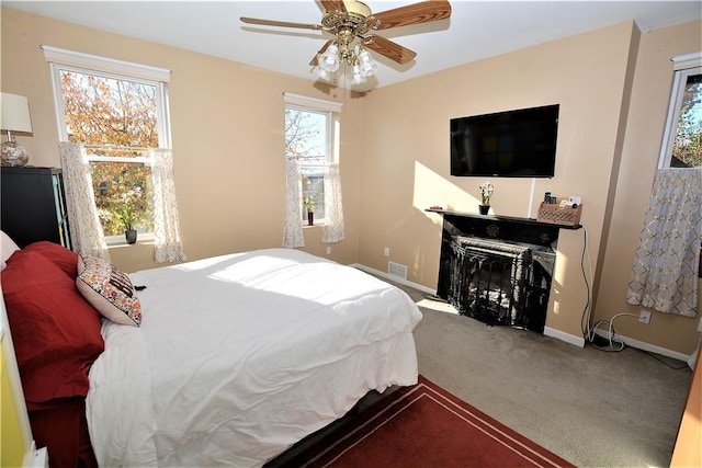 bedroom featuring visible vents, baseboards, a ceiling fan, carpet, and a fireplace