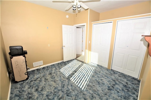 bedroom with two closets, visible vents, carpet flooring, ceiling fan, and baseboards