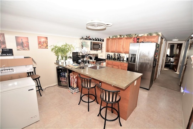 kitchen with wine cooler, stainless steel appliances, a sink, a peninsula, and a kitchen bar