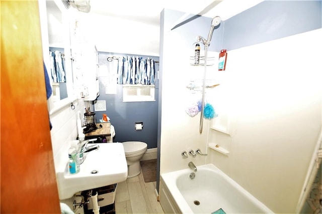 bathroom featuring toilet, washtub / shower combination, and a sink