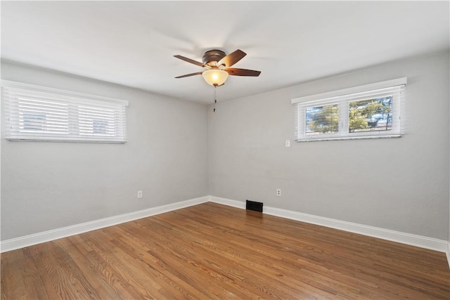 empty room featuring plenty of natural light, wood finished floors, and baseboards