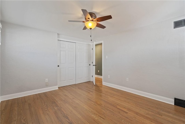 unfurnished bedroom with a closet, visible vents, baseboards, and wood finished floors