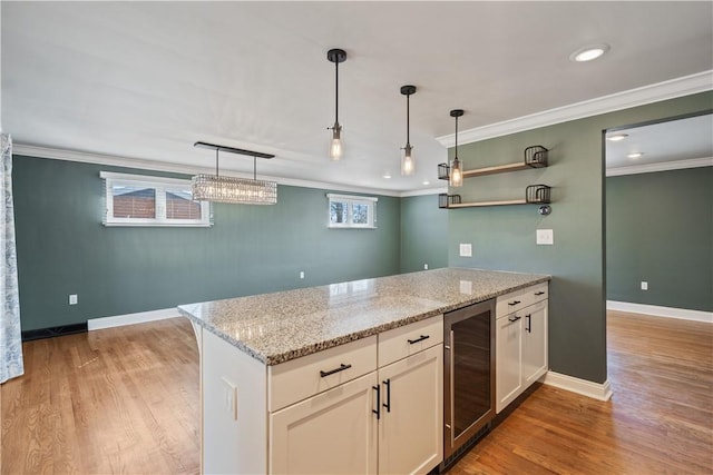 kitchen featuring beverage cooler, a peninsula, light wood-type flooring, and crown molding