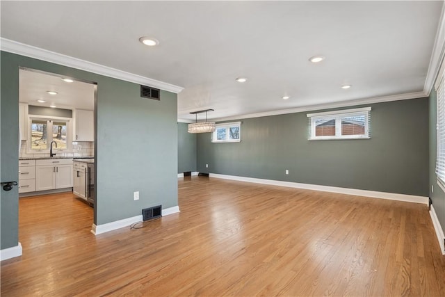 interior space featuring ornamental molding, baseboards, visible vents, and light wood finished floors