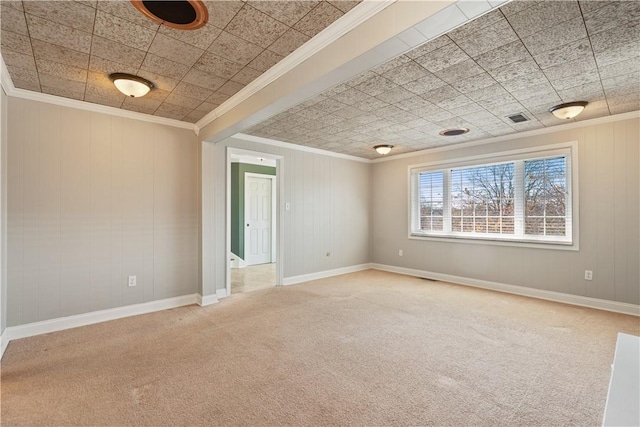 carpeted spare room featuring baseboards, visible vents, and crown molding