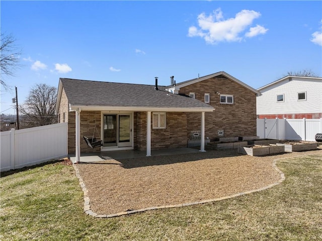 back of house with brick siding, a yard, a vegetable garden, a patio area, and fence private yard