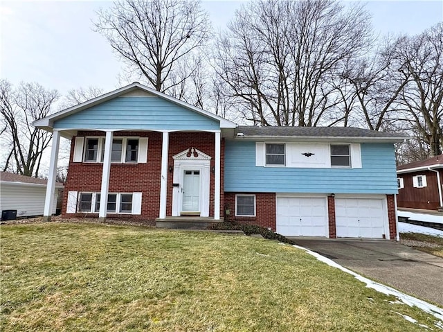 split foyer home with driveway, an attached garage, a front yard, and brick siding