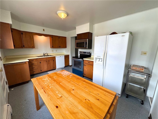 kitchen with brown cabinetry, appliances with stainless steel finishes, light countertops, and a sink