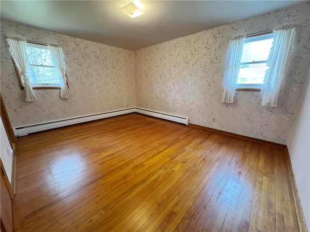 spare room with baseboards, a healthy amount of sunlight, hardwood / wood-style flooring, and wallpapered walls