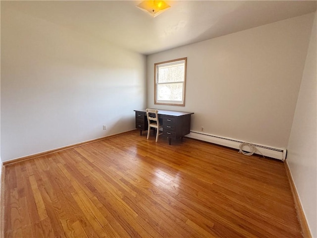 spare room featuring baseboard heating, wood finished floors, and baseboards