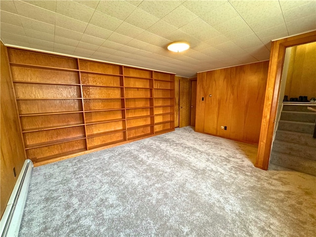 interior space with built in features, stairway, baseboard heating, carpet floors, and wood walls